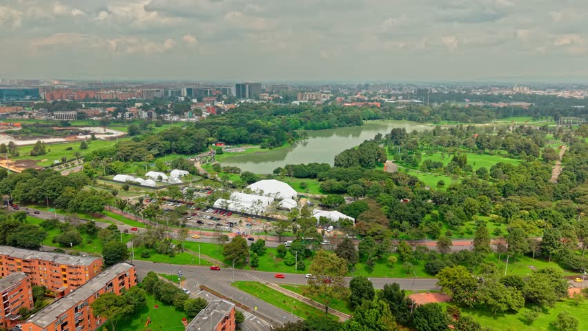 Aerial drone fly green urban Simon Bolivar park in Bogota City, Colombia next to avenue traffic, Teusaquillo neighborhood background