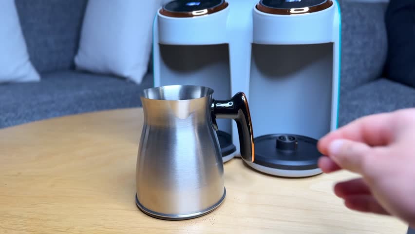 4K close-up of a hand placing a stainless steel coffee pot onto a modern coffee machine on a wooden table—ideal for appliance demos, coffee tutorials, and lifestyle content.