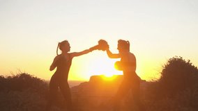 Sporty female fighter practicing boxing on hill overlooking seascape during sunset, with female coach guiding her. Determined boxer training in scenic beach setting - Powered by Shutterstock - Get 15% off with code: PIKWIZARD15