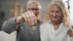 Buy new apartment, keys in hands of elderly man, blurred portrait of aged couple . Mature spouses rejoicing by finish of mortgage, happy house owners, real estate agency, rent, purchase or sale flat - Powered by Shutterstock - Get 15% off with code: PIKWIZARD15