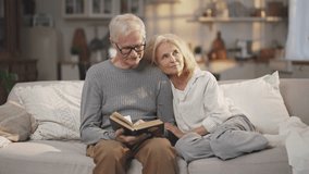 Romantic weekend of aged married couple, aged man reading book for his wife. Mature people spending pastime calmly in village house, happiness and joy in old age, elderly man and woman in cozy room - Powered by Shutterstock - Get 15% off with code: PIKWIZARD15