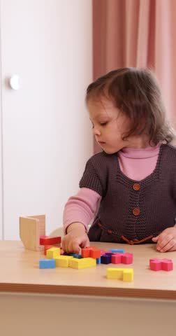 cute little child girl collects 3d puzzle jigsaw puzzle on table