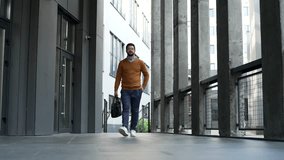 Silhouette. Confident businessman walking outside modern office building with briefcase. Entrepreneur in sweater going to work in urban city setting. Business and entrepreneurship. Front view - Powered by Shutterstock - Get 15% off with code: PIKWIZARD15