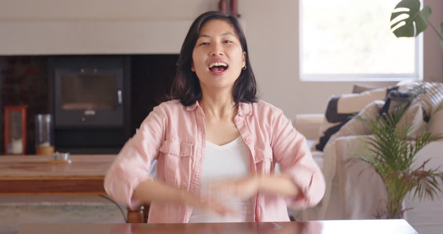 Close up of people talking to the camera, Sitting at table, woman clasping hands and smiling in cozy home setting.
