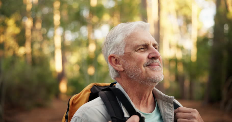 Breathe, senior man and walk in woods for hiking adventure, retirement hobby or cardio fitness. Mature person, relax and journey with backpack for trekking, explore or holiday sightseeing in forest