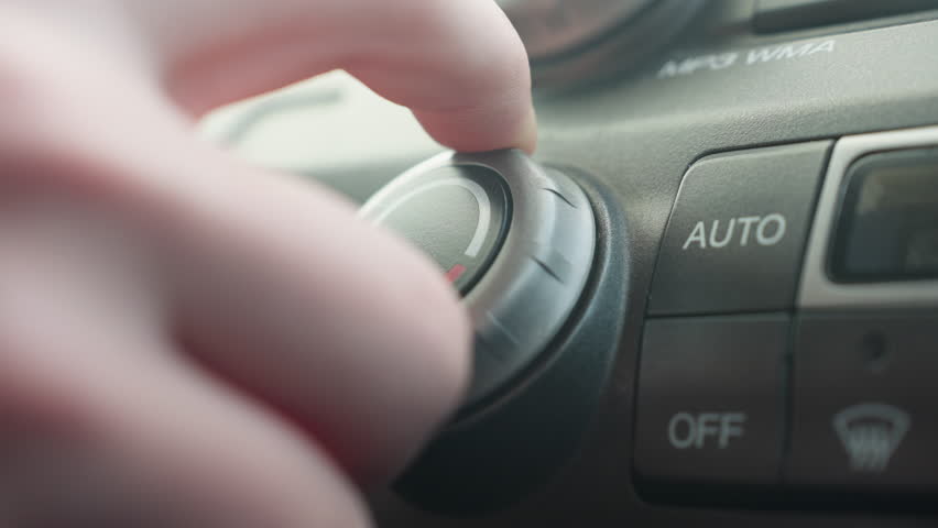 close up finger pressing off button on car air conditioning control panel with illuminated icons showing recirculation and defrost for authentic cabin interior detail softly under ambient light