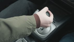 Close up top down view of driver pushing gear shift lever into park position in car center console showing hand grip on leather knob and metallic base under soft daylight in modern interior - Powered by Shutterstock - Get 15% off with code: PIKWIZARD15