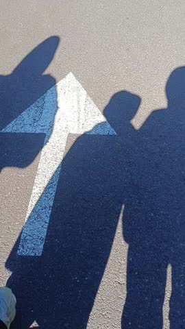 We are walking as a family. Our shadows are reflected on the asphalt
