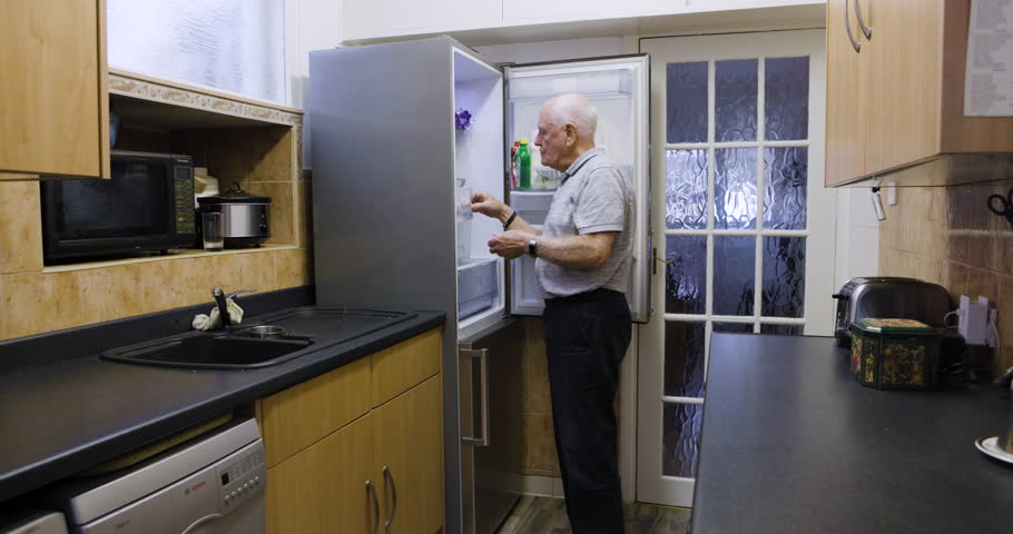 Senior man, refrigerator and open door for food choice while thinking, eating and hungry in home kitchen. Elderly person at fridge to prepare meal, lunch or dinner in retirement in Uk house alone