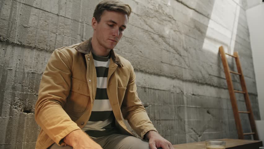 A man in quiet prayer leans over an open Bible, hands clasped, surrounded by candlelight and a peaceful indoor setting.