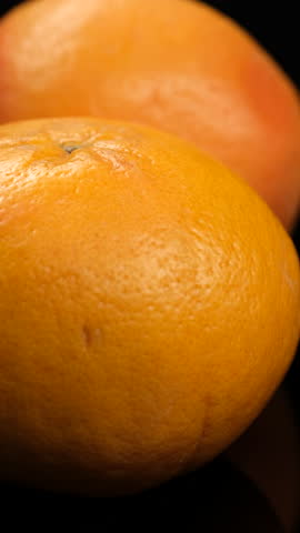 Whole grapefruit macro on black background, rotation