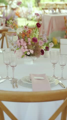 Vertical video. Table decor features fresh, vibrant flowers, elegant glasses, and a lovely delicate pink theme. Wedding day