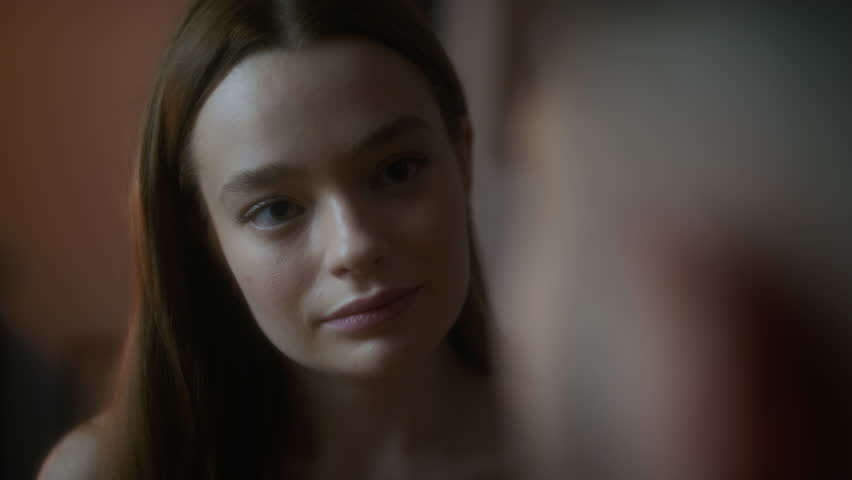 Over shoulder close-up shot of man looking at pretty young Caucasian lady and gently touching her face, enjoying intimate moments with girlfriend at home