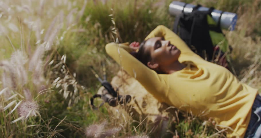 Woman lying on rock in sunlit field, showing floating social media icons for content marketing. Nature, relaxation, outdoor, serenity, digital, social media, lifestyle