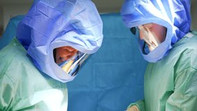 Smiling Caucasian male surgeons in protective helmets cooperate at surgery. Doctors perform operation on trauma. - Powered by Shutterstock - Get 15% off with code: PIKWIZARD15