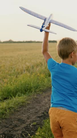 Boy child run in field through wheat field, play with toy airplane in their hands, dream of flying. Child dreams of fly. Child plays with his toy plane. Child boy run dream travel. Happy family nature