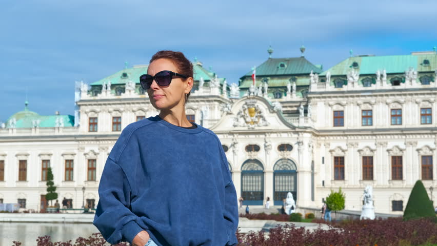 Tourist admiring belvedere palace in vienna. Young woman tourist wearing sunglasses and casual clothes looking at upper belvedere palace, vienna, austria