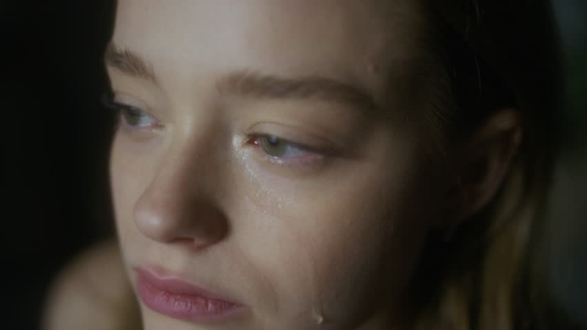 Extreme close-up shot of young tearful Caucasian woman with green eyes crying in pain after breakup and looking away, feeling vulnerable and lonely, missing ex-love