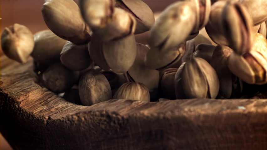 Pistachios fall into a wooden bowl. Filmed on a high-speed camera at 1000 fps. High quality FullHD footage