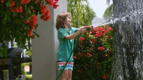 Child planting and watering flowers. Gardening fun with a child. Little kid growing plants in the backyard. Summer watering fun with a child. Child playing in the garden with a watering can. - Powered by Shutterstock - Get 15% off with code: PIKWIZARD15