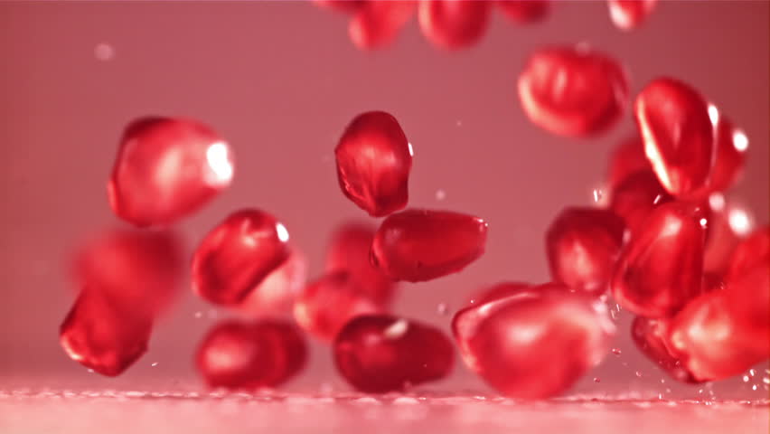 Pomegranate seeds fall on the table with splashes. Filmed on a high-speed camera at 1000 fps. High quality FullHD footage