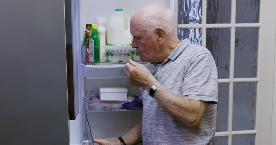 Hungry, decision and senior man at fridge, thinking and diet for health with fruit. Idea, retirement and elderly person with choice at the refrigerator for a food snack with nutrition in the kitchen