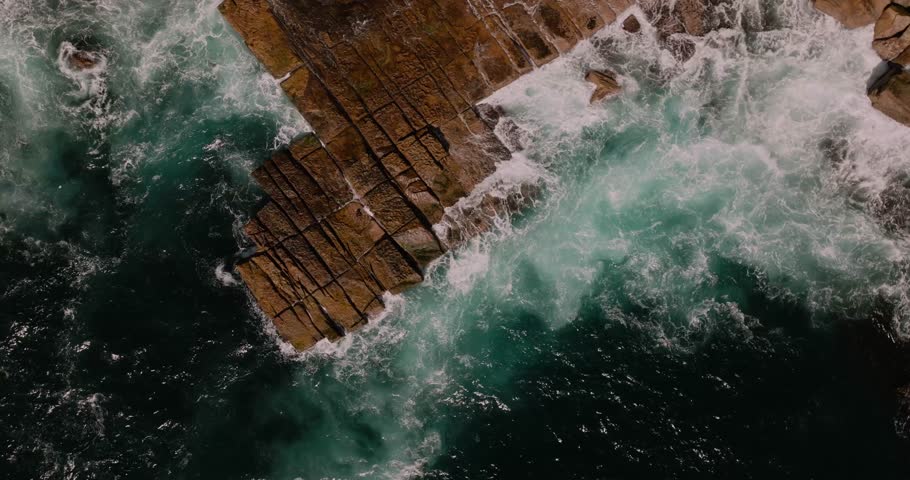 waves crash and wash dramatically over slab of rocks