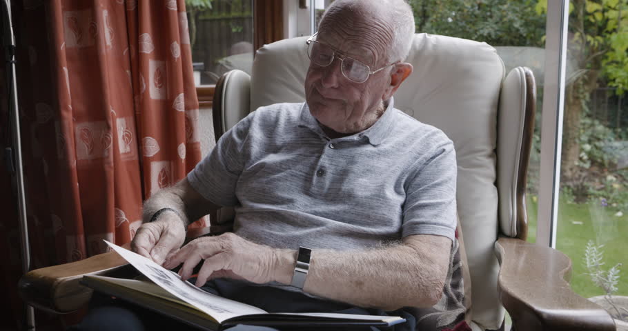 Senior man, reading book and relax on the couch in home with glasses, sofa, calm and peace in living room. Content, retired and elderly male, literature and read novel, story and relaxing on couch