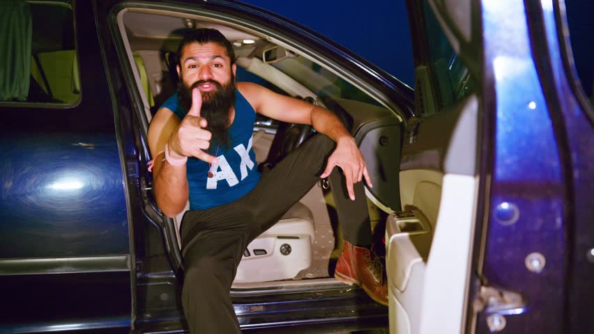 Rap artist gesturing with hands while dancing, Bearded hip hop star dances in an unlatched car, Freestyle Urban dancer moves on music video boldly, Passionate guy enjoying song seated at the front