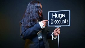 Promoter holds signage pointing massive deal at trade fair, Woman holding huge discount signboard in exhibition, Advertiser raises banner announcing best bargain, Model displays flash sale by showroom - Powered by Shutterstock - Get 15% off with code: PIKWIZARD15
