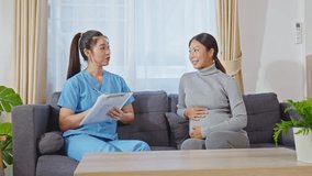 Asian nurse or doctor in blue scrubs holds clipboard while consulting with pregnant woman during prenatal care visit at home or st premium private clinic or hospital in a cozy environment - Powered by Shutterstock - Get 15% off with code: PIKWIZARD15