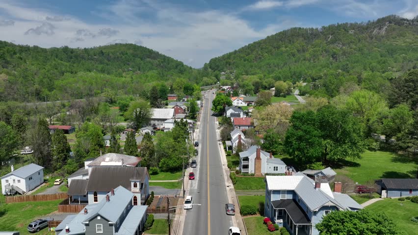 Straight street of idyllic small american town with green mountains. Sunny day in spring. Wide shot. Lovingston, Virginia. Flying bees and flies in camera lens of drone.