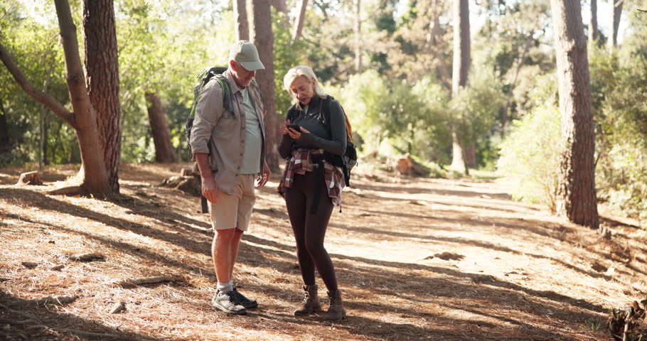 Phone, hiking and couple outdoor for navigation, destination discussion or lost in woods. Mobile, senior man or woman in forest with map for trekking, pointing or direction on location app for travel