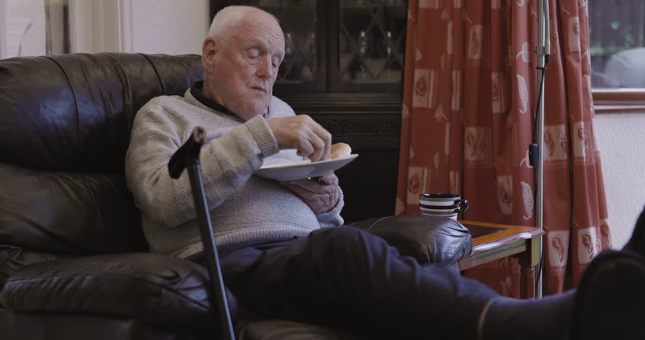Retirement, senior and man eating and relax sitting on a couch or sofa resting, break and enjoying a snack, lunch or food. Elderly, pensioner and old person is retired holding a plate in a house
