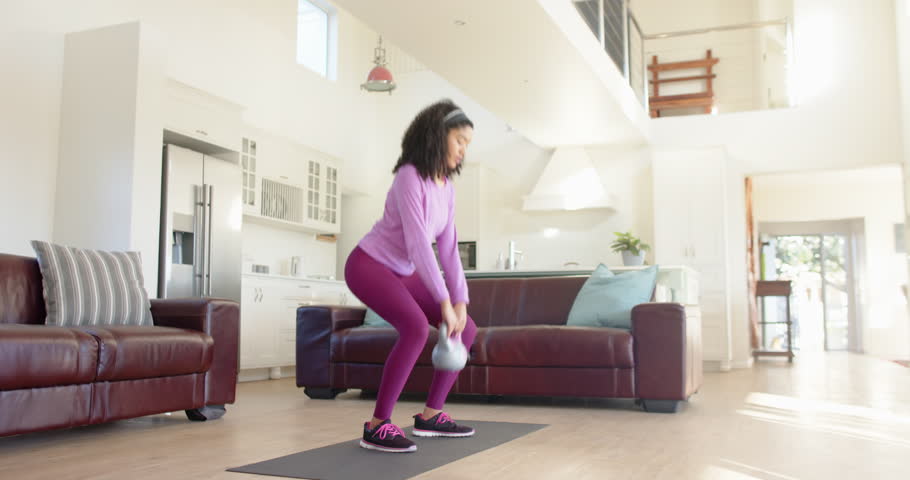 Lifestyle videos indoor of people doing activities at home, exercising at home, woman lifting kettlebell on yoga mat in living room. person working out indoor, working out with weights