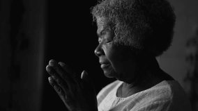 One devoted Religious black senior woman PRAYING to GOD at home by window in monochromatic, black and white. Spiritual African American elderly lady in deep meditation - Powered by Shutterstock - Get 15% off with code: PIKWIZARD15