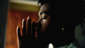 Profile close-up face of a young black man PRAYING to GOD. Meditative African American person with eyes closed engaged in devotion - Powered by Shutterstock - Get 15% off with code: PIKWIZARD15
