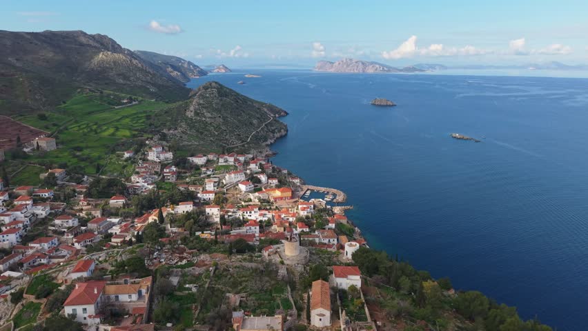 Panoramic aerial footage of Hydra Island, Greece. Sweeping views of the coastline, hills, and traditional architecture surrounded by the deep blue Aegean Sea.