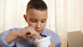 Boy eating yogurt while sitting at the table - Powered by Shutterstock - Get 15% off with code: PIKWIZARD15