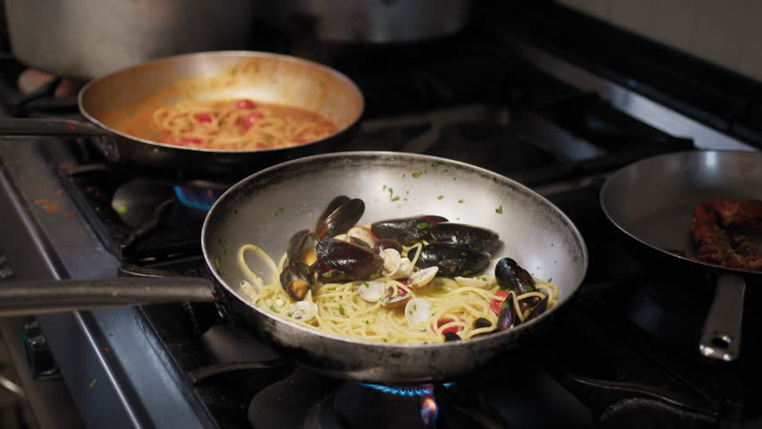 Chef Using Different Pans While Cooking Pasta With Seafood