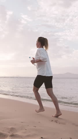 Beautiful slender woman running on picturesque shore of ocean, morning jog. Healthy lifestyle for stay young and slender in middle age, physical exercise outdoors, athletic female person training