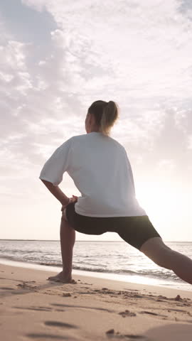 Woman doing yoga exercise on sea shore in morning, slow motion, sport workout. Healthy lifestyle for stay young and beautiful in middle age athletic female person stretching body, breathing fresh air