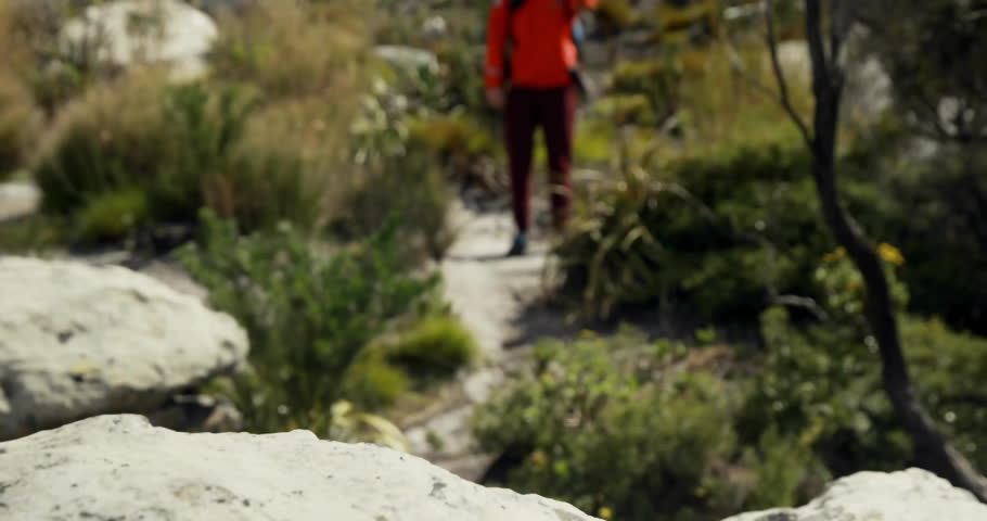 Man hiking rocky trail near cairn, passing translucent tech icons showing likes comments alerts. Adventure, exploration, nature, rugged, outdoor, trail, fitness