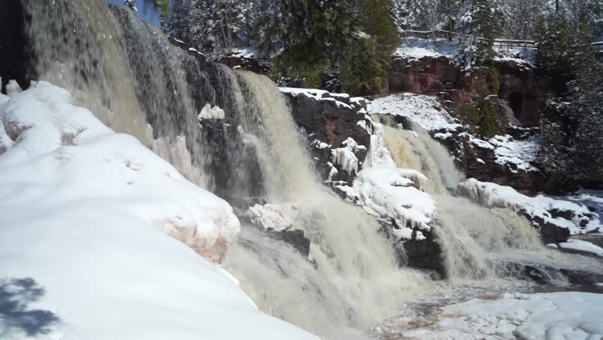 Panorama Of Winter Landscape At Gooseberry Falls State Park In Minnesota, With Waterfall Cascading Down An Icy River. panning shot