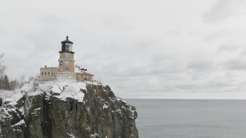 Rocky Cliff With Lighthouse At Split Rock State Park By The Lake In Winter In Minnesota, USA. - aerial shot