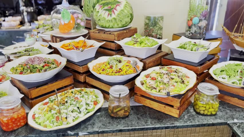 4K shot of a vibrant salad bar buffet with a variety of fresh greens, vegetables, and pickles on wooden platters. Great for healthy food, catering, or restaurant visuals.