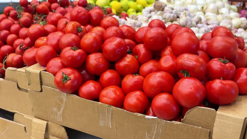 A 4K close-up of ripe red tomatoes stacked in a grocery market. Ideal for food, health, cooking, farming, or organic produce themes with vibrant natural color and texture.