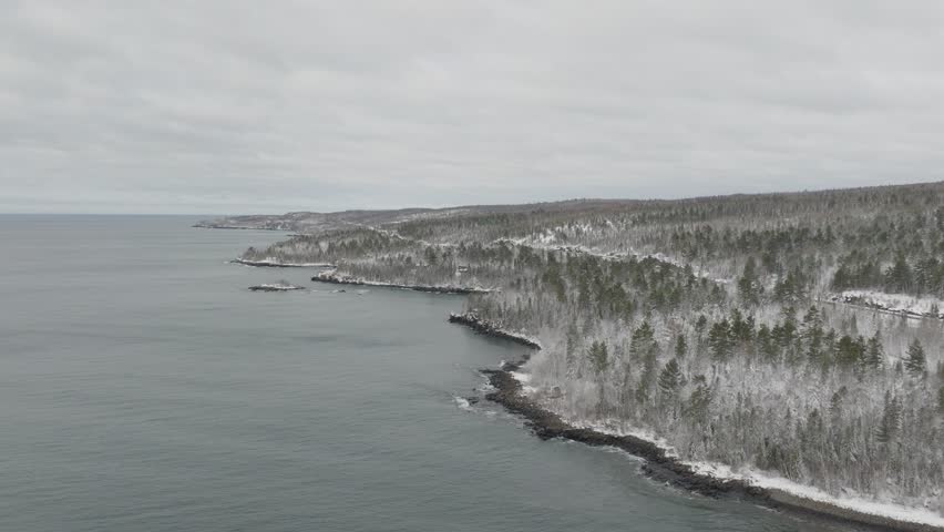 Snow-covered Forest Trees On Shore Of Lake Superior In Winter. Minnesota, USA. wide drone shot