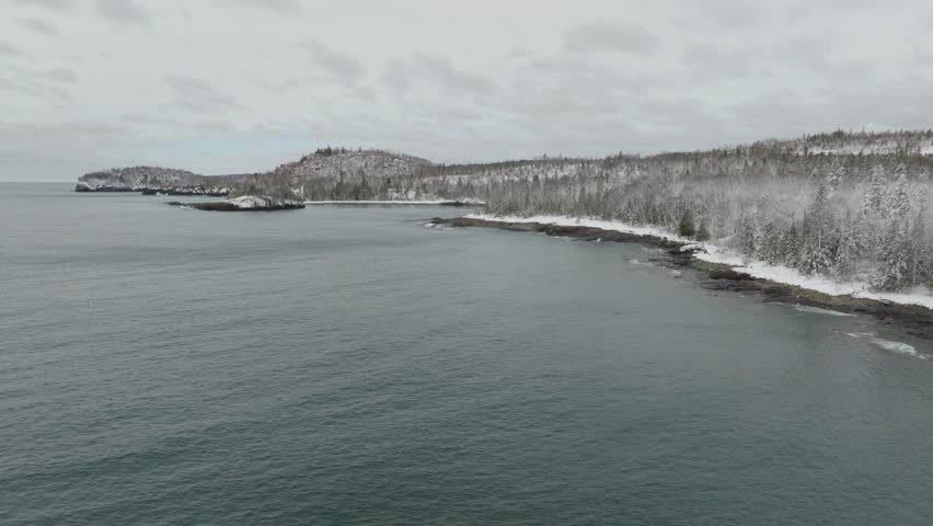 Lake Superior And Snow-covered Forest In Winter From Split Rock Lighthouse State Park In Minnesota, USA. - aerial pullback shot