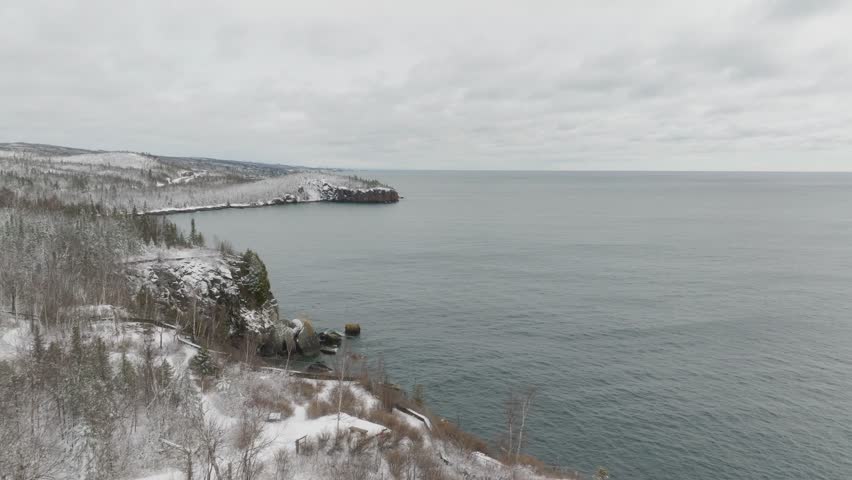 Pullback Reveal Of Historic Split Rock Lighthouse On Snowy Cliff, Overlooking Lake Superior With Overcast Sky In Minnesota, USA. wide drone shot